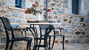 A stone building with a window and a table with chairs. - Lithos Stone Suites (East Mani)