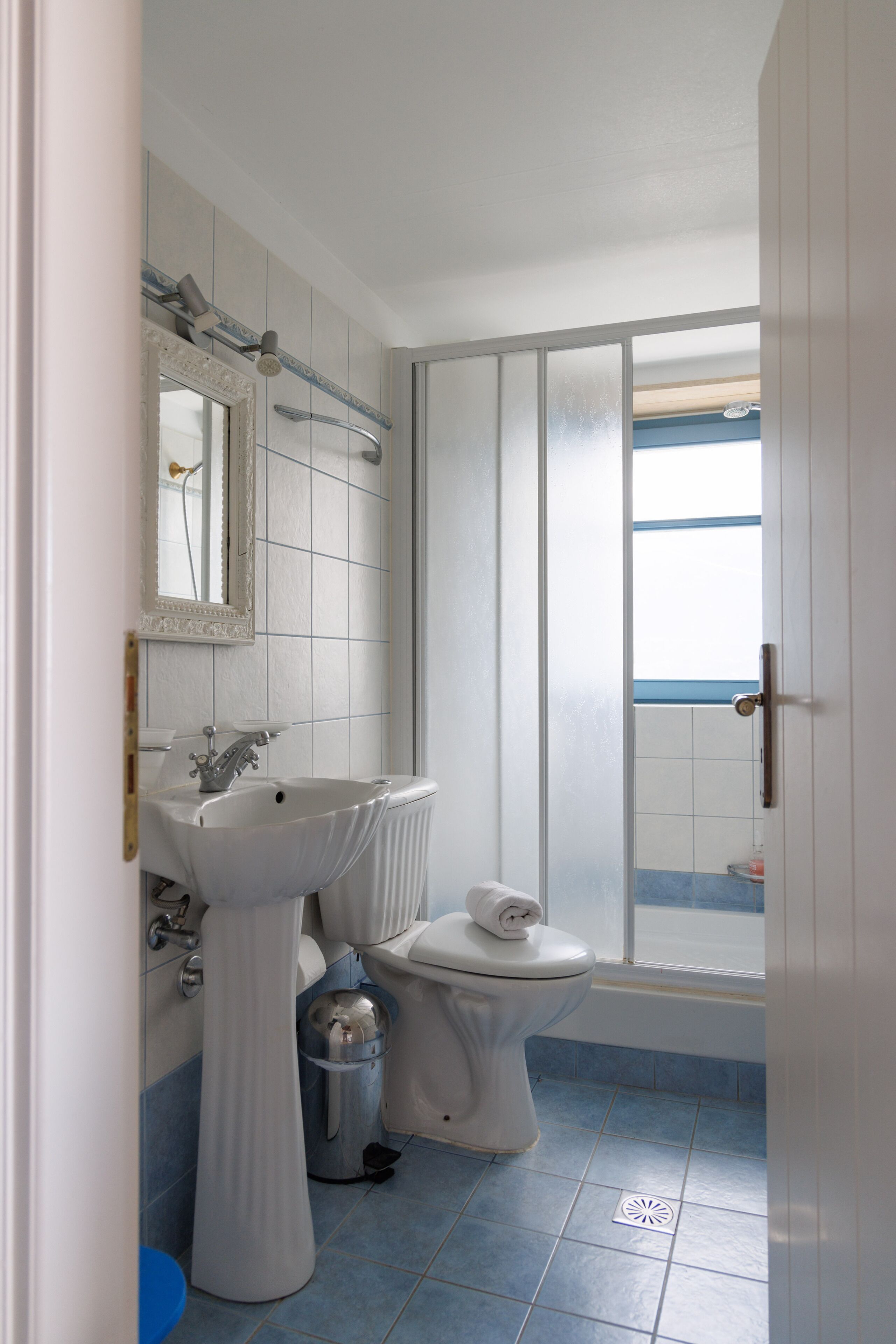 Une salle de bain avec un lavabo, des toilettes et une douche, le tout de couleur blanche.