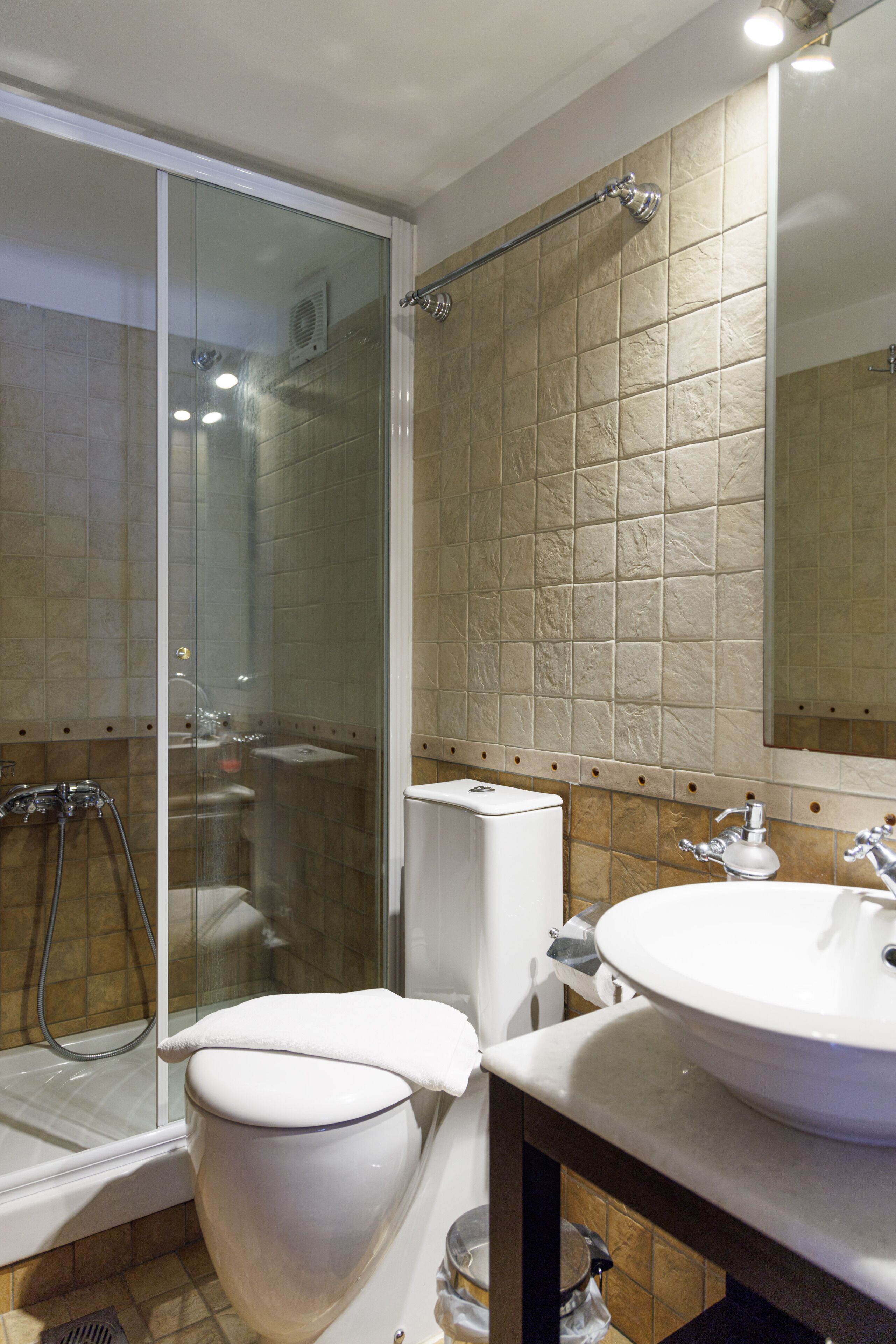 A bathroom with a glass-enclosed shower, a toilet, and a sink.