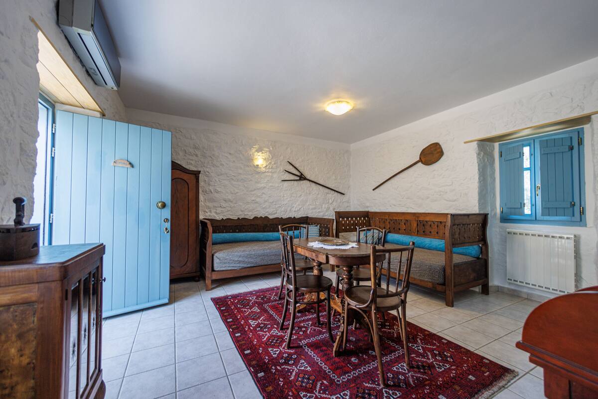 A room with a wooden dining table, blue upholstered bench, and a red patterned rug.