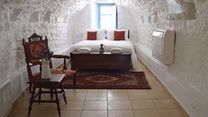 Una habitación acogedora con una cama, una silla de madera, una mesita pequeña y un radiador.