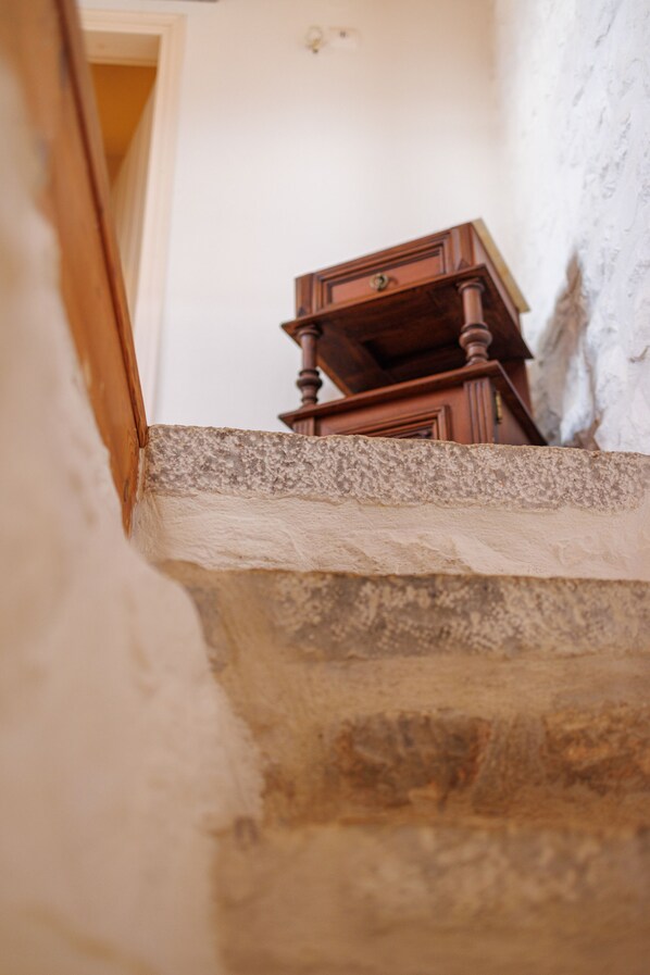 Un aparador de madera sobre un repisa de piedra en una habitación con pared blanca texturizada.