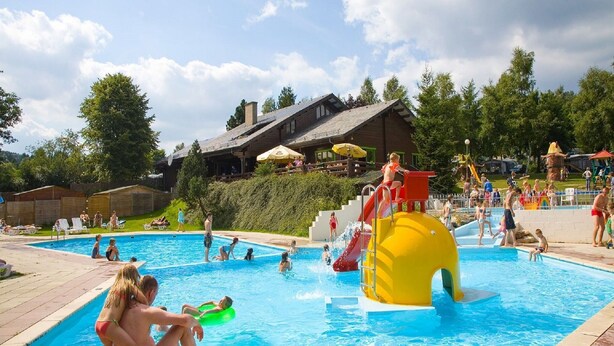 A swimming pool area with a water slide and lounge chairs. - Escape in Dochamps Chalet (Manhay)