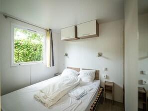 A bedroom with a bed, a window, and a small bedside table. - Charming Chalet with Pool (Dochamps)