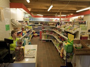 A grocery store interior with shelves stocked with various products, a checkout counter, and a customer service area. - Charming Chalet with Pool (Dochamps)