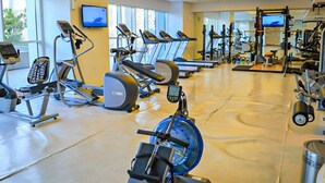 A gym with various exercise equipment, including treadmills, stationary bikes, and weight machines. - AST - Modern studio flat with balcony (Dubai)