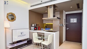 A compact kitchen with a dining area, a flat-screen TV, and a microwave. - AST - Modern studio flat with balcony (Dubai)