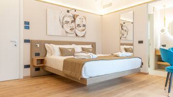 Un dormitorio moderno con una cama grande, suelo de madera y obras de arte en las paredes.
