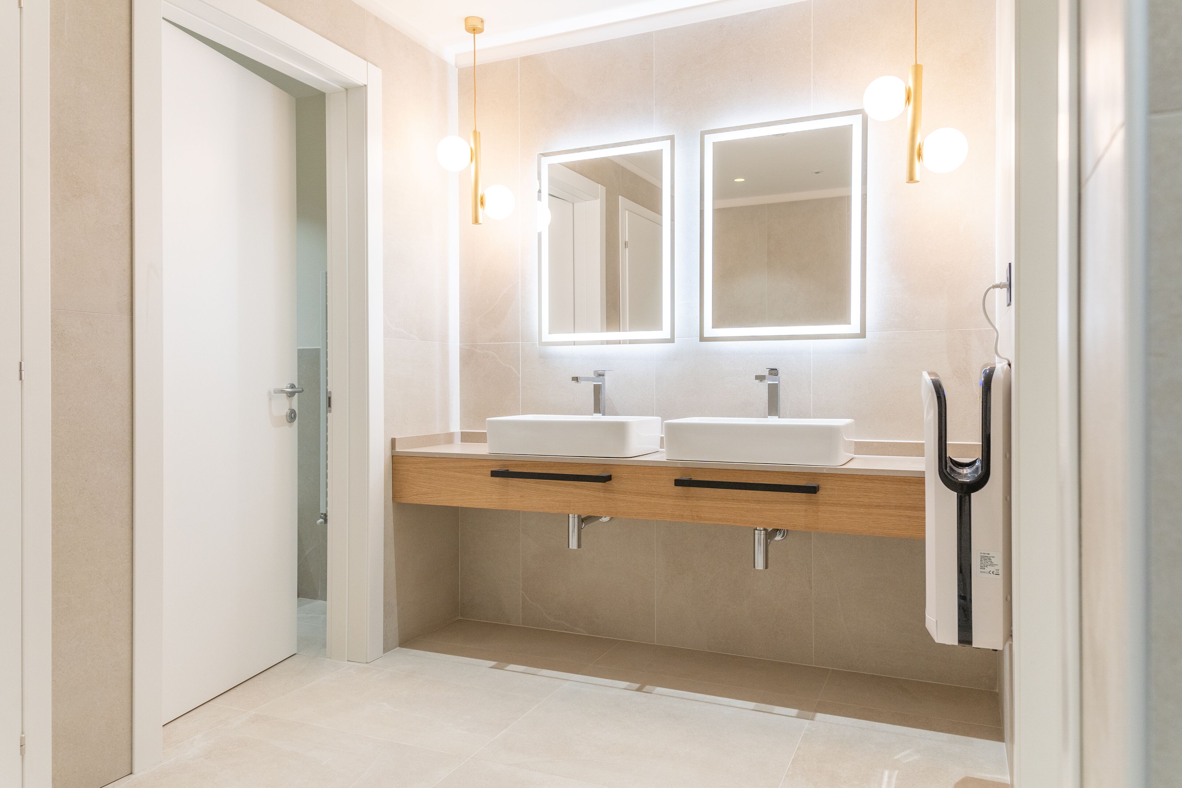 A modern bathroom with two sinks, a mirror, and a towel rack.