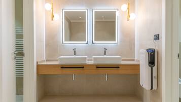 Un bagno moderno con due lavabi, uno specchio e un asciugamani ad aria.