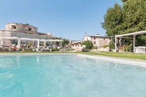 A swimming pool with lounge chairs and umbrellas, a stone building, and a tree. - Forte Benedek Wine Relais & SPA - Adults Only (Pastrengo)