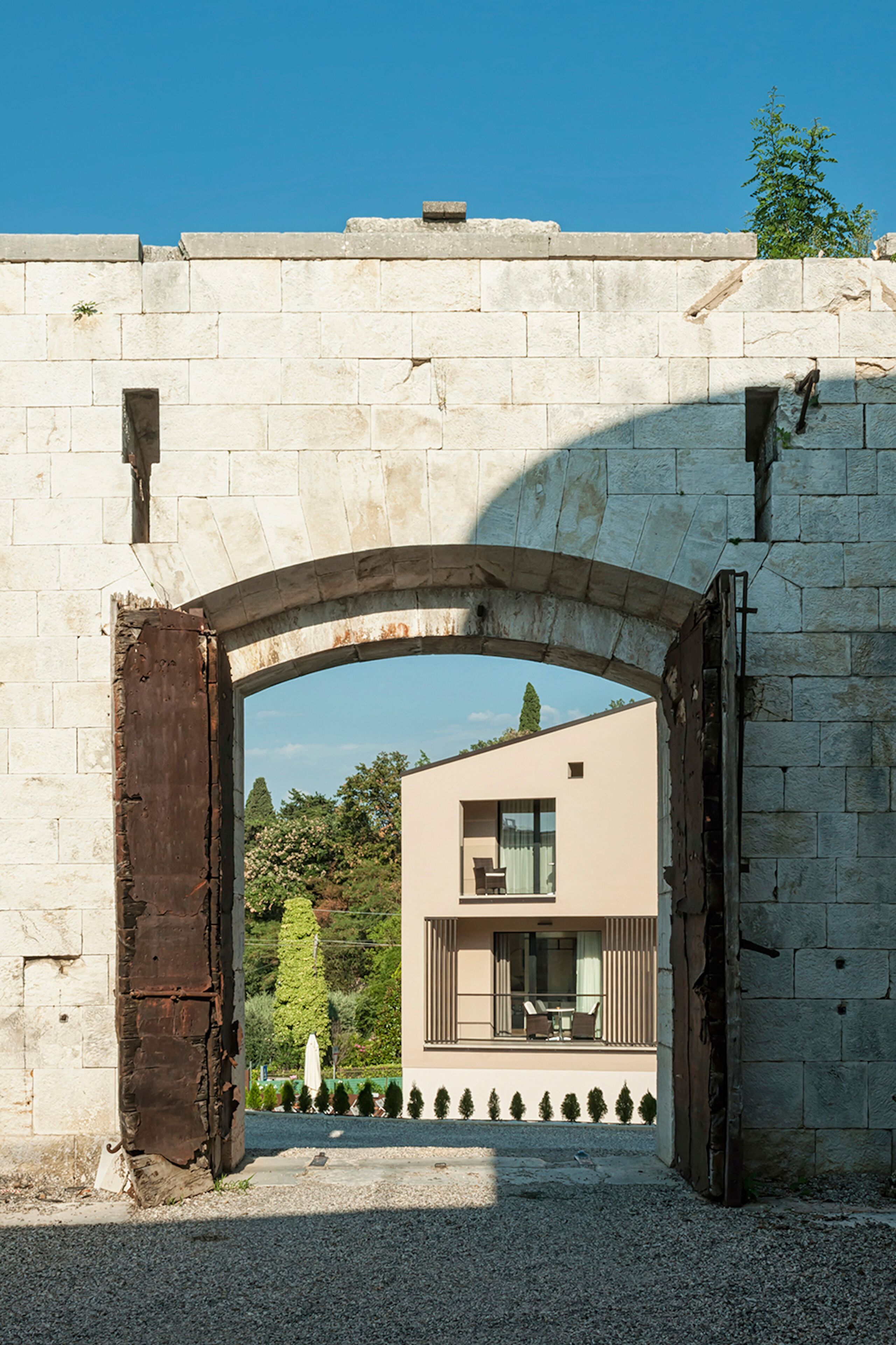 Un arco de piedra que da acceso a un edificio moderno con balcón y zona de estar.
