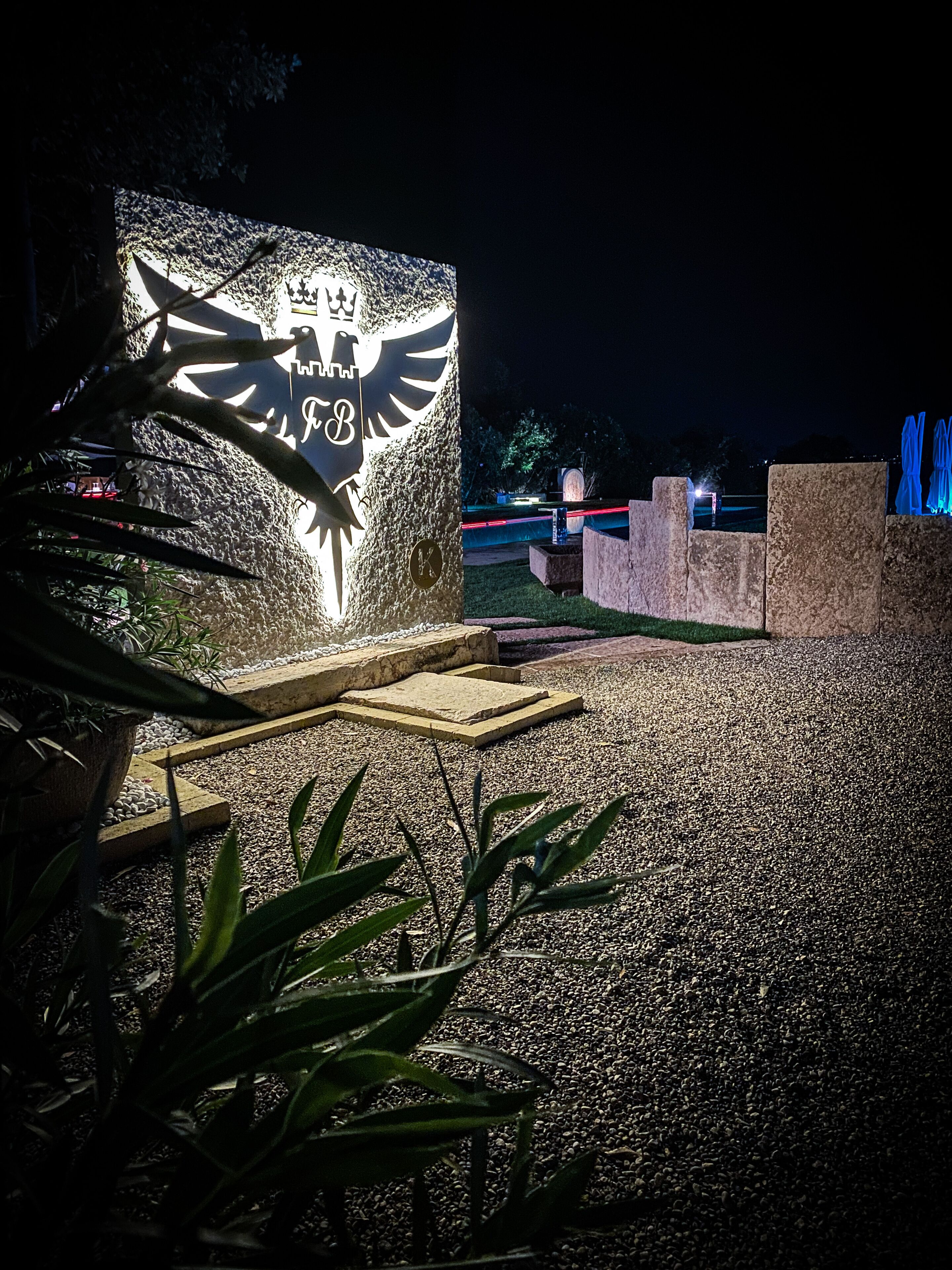 Un monumento de piedra con un águila y las letras "F.B." iluminadas en la noche.