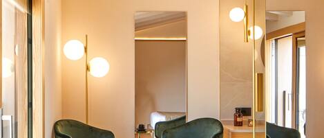 Una habitación moderna con dos sillas verdes, una mesita redonda y un espejo.