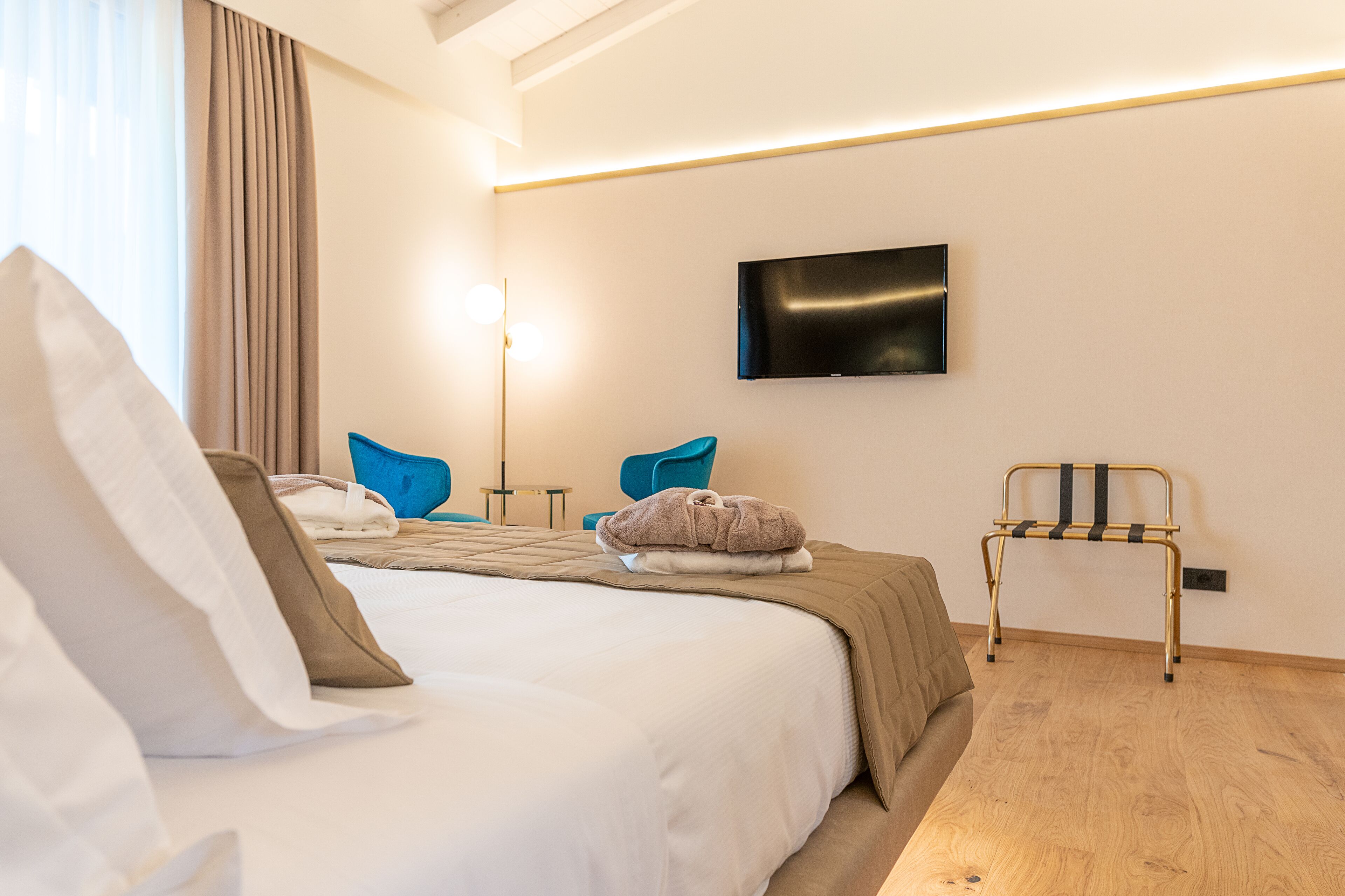 Ein modernes Hotelzimmer mit einem großen Bett, einem flachbildfernseher an der Wand, einem Nachttisch und einem Sessel.
