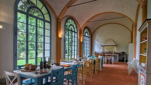 Un comedor con una mesa larga, sillas y una cocina al fondo.