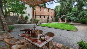An outdoor patio with a table set for dining, wicker chairs, and a pergola overhead. - Cozy Villa for Six Guests (Sinalunga)