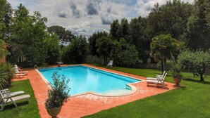 A rectangular swimming pool with a tiled deck, surrounded by a well-maintained lawn and trees. - Cozy Villa for Six Guests (Sinalunga)