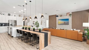 Una cucina moderna con isola centrale, illuminazione a sospensione e un'ampia zona pranzo.