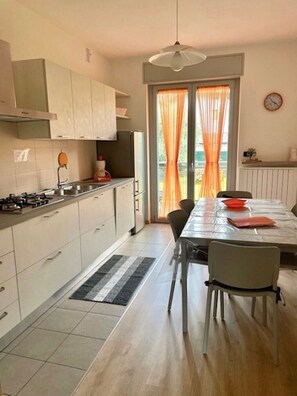 Une cuisine moderne comprenant un coin repas, une cuisinière, des placards et une fenêtre avec des rideaux.