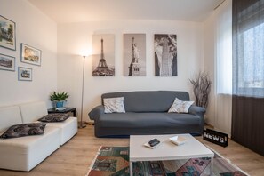 A modern living room with a grey sofa, a white coffee table, and a patterned rug.