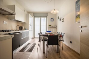 A modern kitchen with a dining area, a built-in oven, and a large window.