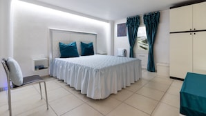 Un dormitorio con cama, una silla, un armario y una ventana con cortinas.