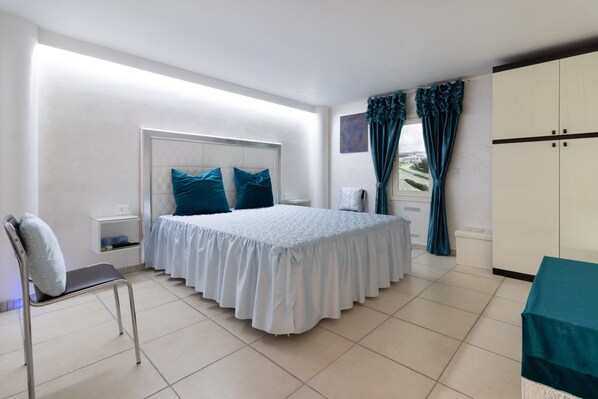 A bedroom with a bed, a chair, a wardrobe, and a window with curtains.