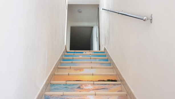 Una escalera con un mural del atardecer pintado en los peldaños.