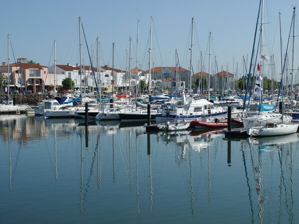 Un puerto deportivo con varias embarcaciones amarradas, rodeado de edificios con tejas rojas.