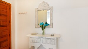 A white console table with a mirror above it, a vase with blue flowers, and a wooden door to the left. - Apartment "Nav 4C 4pC" with Sea View & Terrace (Torrevieja)