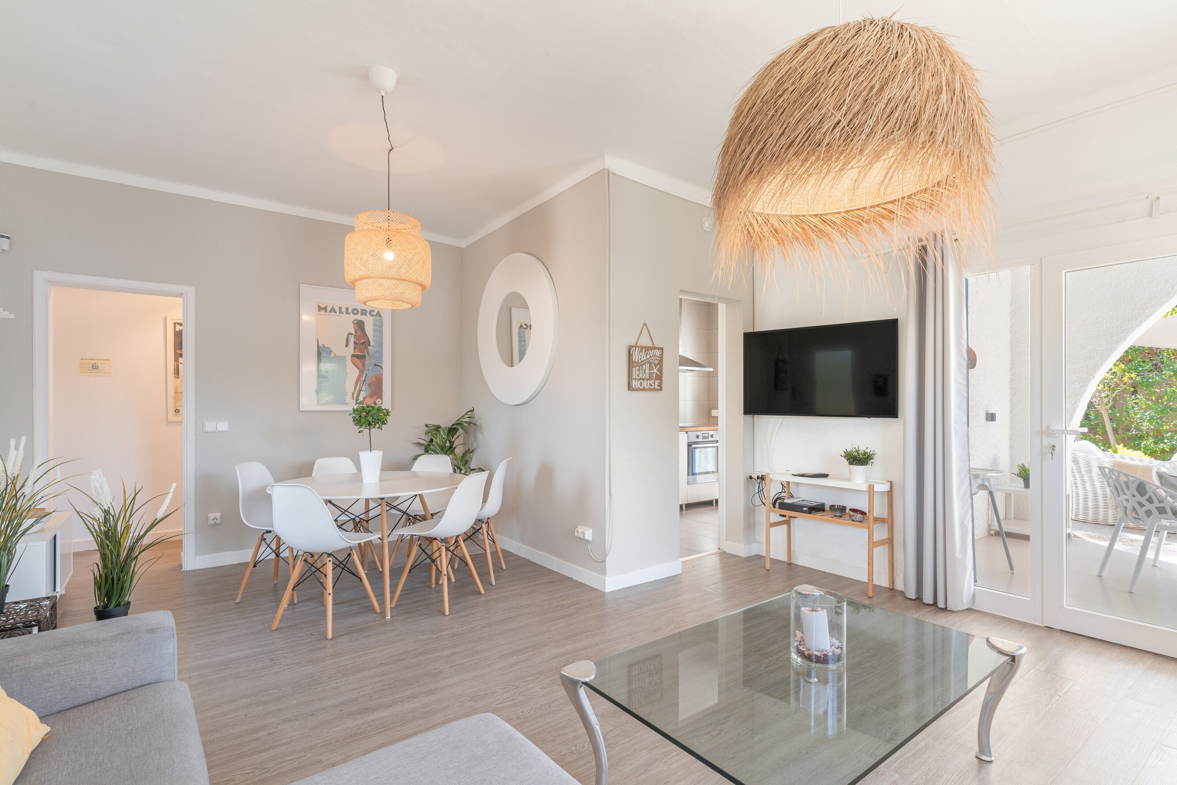 Een moderne woonkamer met een glazen salontafel, een witte eethoek en een grote televisie.