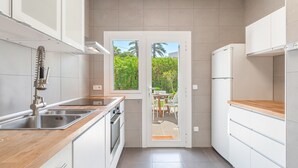 Een moderne keuken met witte kasten, roestvrijstalen apparatuur en een houten aanrecht.