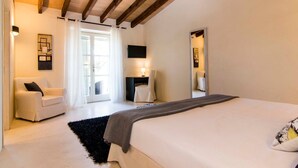A bedroom with a bed, a chair, a desk, a lamp, and a mirror.