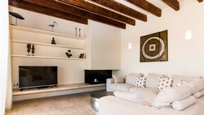A modern living room with a flat-screen TV, a sofa, and decorative items on shelves.