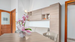 Un comedor moderno con una mesa de madera, un florero y un sofá de color claro.