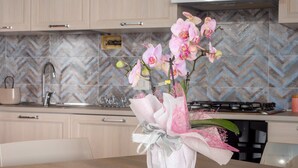 Una cocina con un jarrón de orquídeas rosadas sobre una mesa de madera.