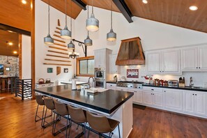 A modern kitchen with a large island, white cabinetry, and hanging pendant lights.