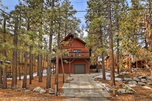 Escape to a secluded cabin surrounded by a dense forest, featuring a spacious porch and balcony.