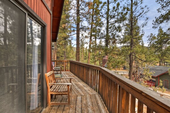 Enjoy the serene forest views from this deck with a bench and table, perfect for taking in the natural surroundings.