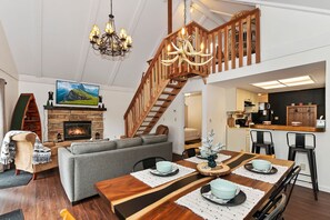 Cozy living area with a grand staircase, fireplace, and flat-screen TV.