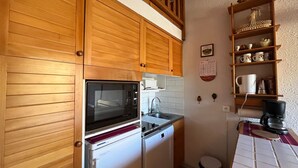 A compact kitchen with wooden cabinets, a built-in oven, a sink, and a coffee maker. - Duplex T2 apartment on slope for 6 people with ski box in Super-Sauze (Enchastrayes)