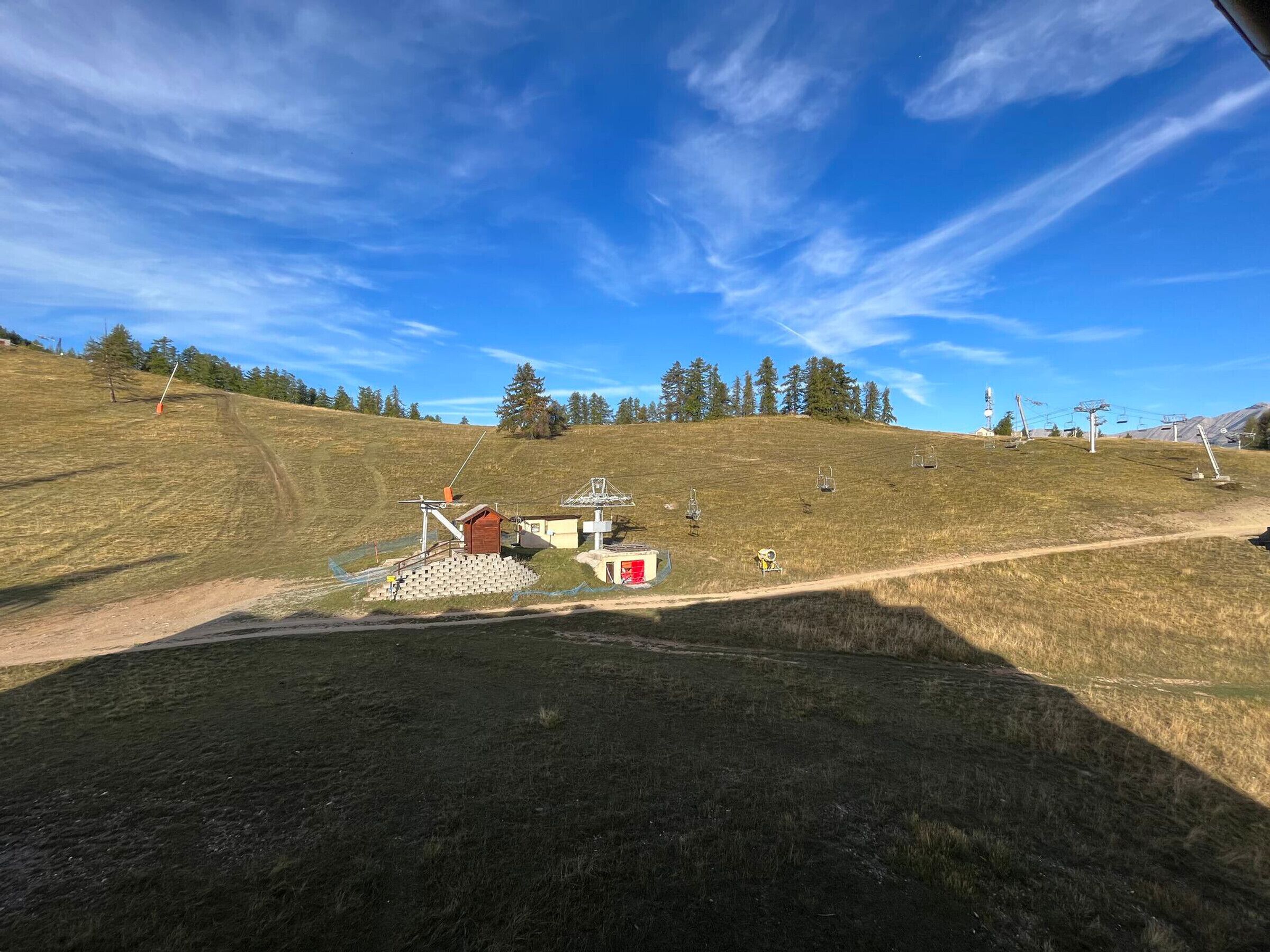 A ski lift area with a small cabin, a chairlift, and a dirt path.