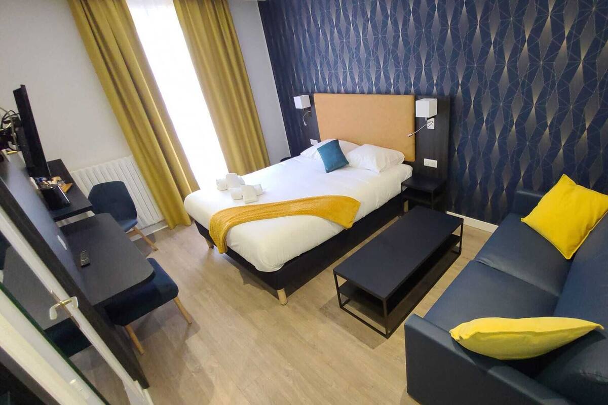 A hotel room with a bed, a sofa, a desk, and a chair.