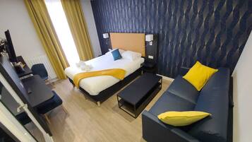 Une chambre d’hôtel avec un lit, un canapé, un bureau et une chaise.