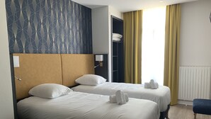 A hotel room with two beds, a wardrobe, a desk, and a window with curtains. - Le Cosy Riva Bella (Ouistreham)