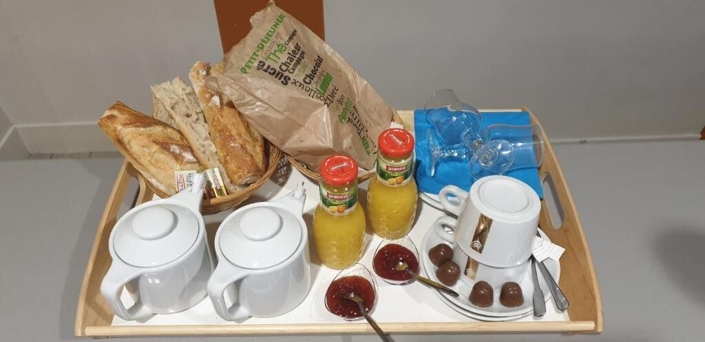 Un plateau de petit-déjeuner avec du pain, de la confiture, du jus et des tasses de café.