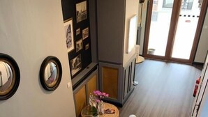 A staircase with a white balustrade leading to a landing with a small round table and framed pictures. - Le Cosy Riva Bella (Ouistreham)