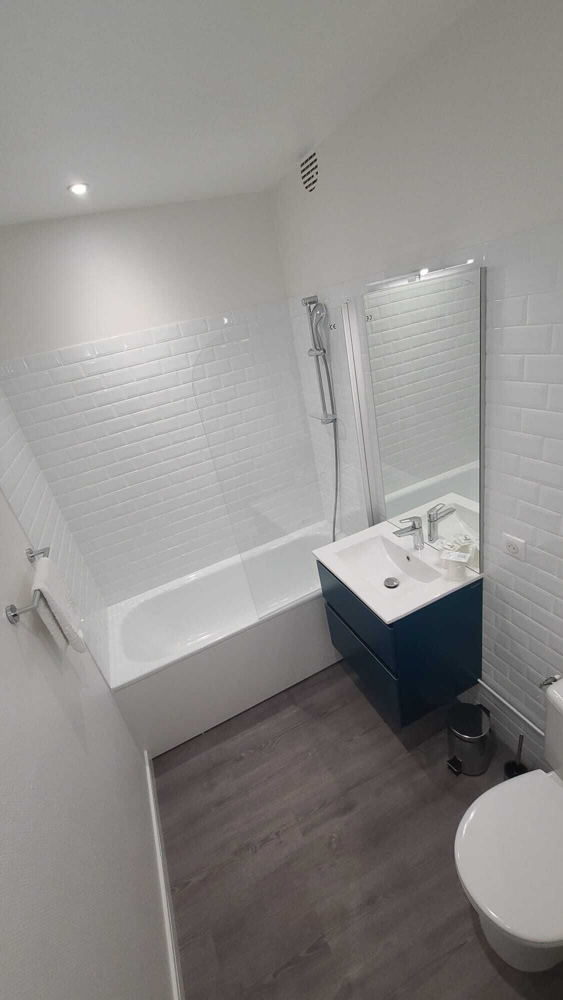 Une salle de bain moderne avec une baignoire blanche, un lavabo avec un miroir et des toilettes.