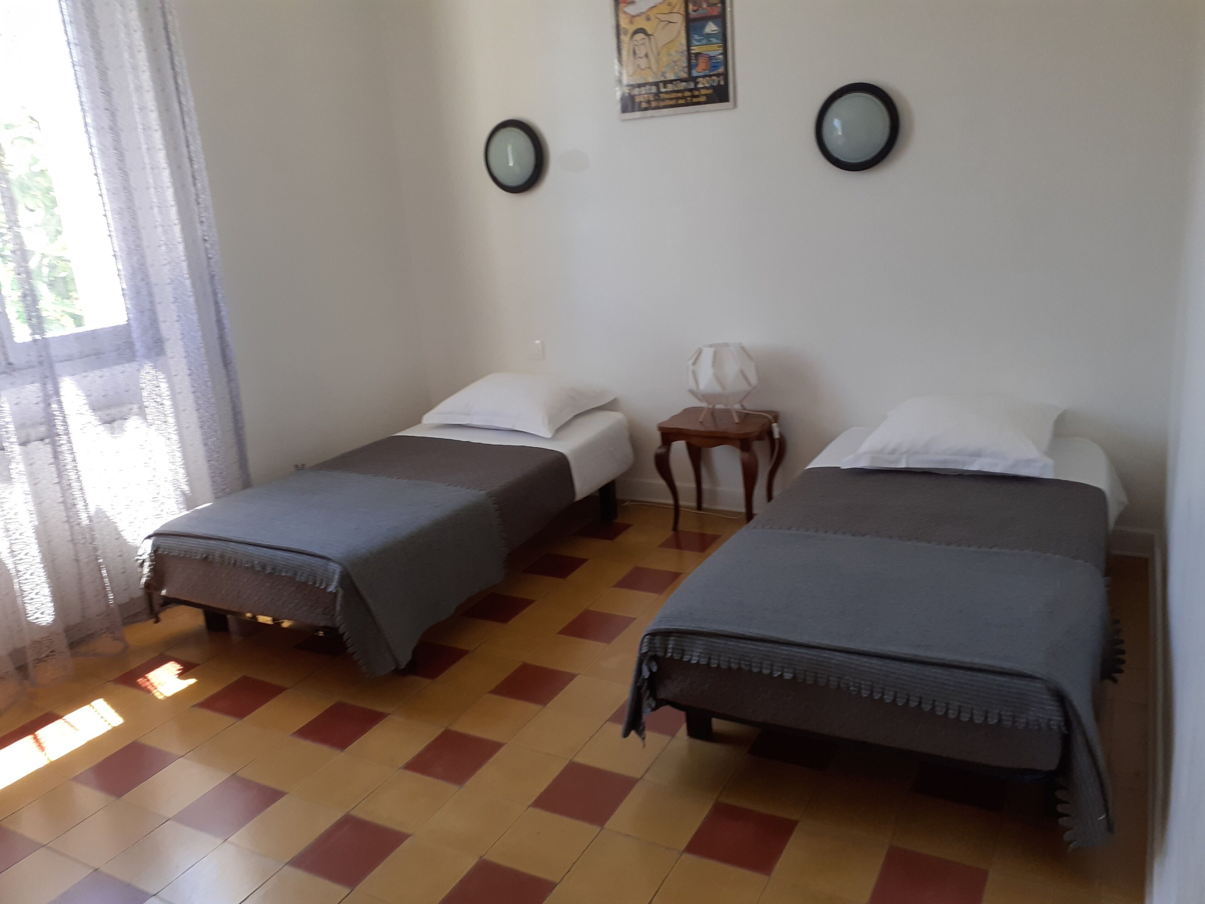 Habitación de hotel con dos camas individuales, una mesita de madera y un reloj de pared.